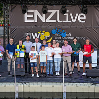 Menschen stehen auf einer Bühne und schauen in die Kamera