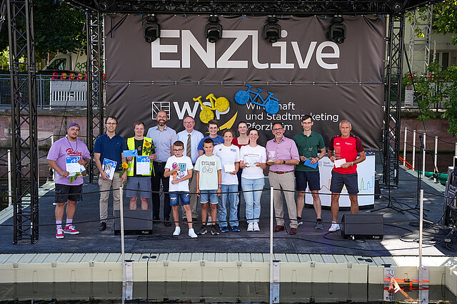 Menschen stehen auf einer Bühne und schauen in die Kamera